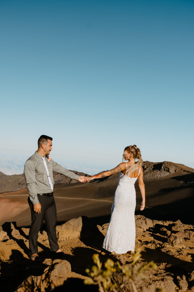 A bride leads her groom around while they explore Haleakala National Park
