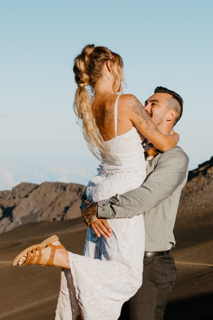 A husband lifts up his wife in celebration of their elopement in Maui, Hawaii. 