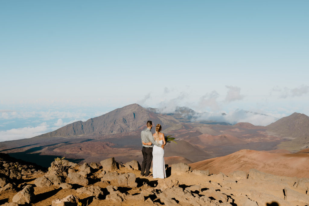 A newly married couple looks out onto Haleakala National Park while on top of a summit
