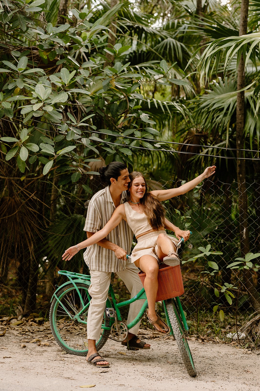 A woman and man share a bike after their engagement on a tropical destination wedding trip