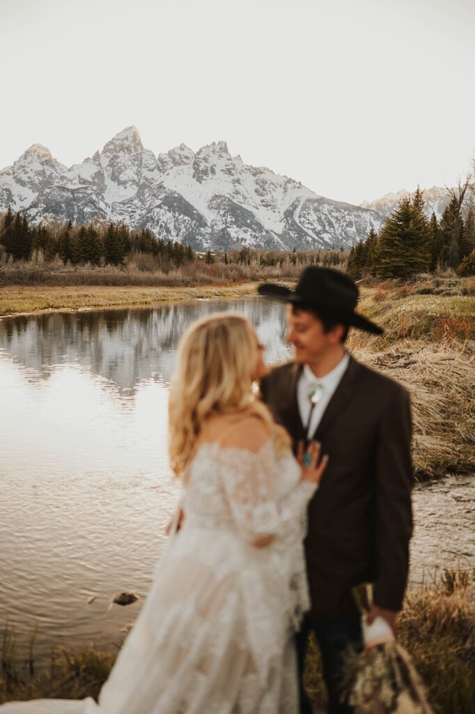A couple is pictured in front of a snowy mountain range after their intimate wedding