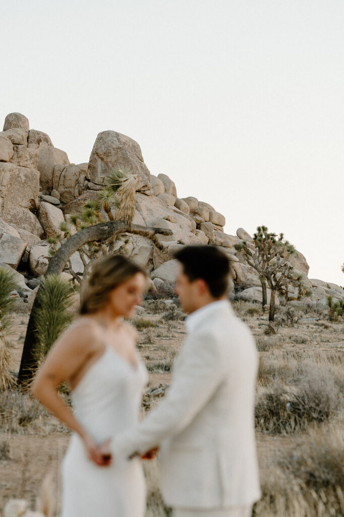 A man and woman hold hands during their Joshua Tree elopement at Sunset