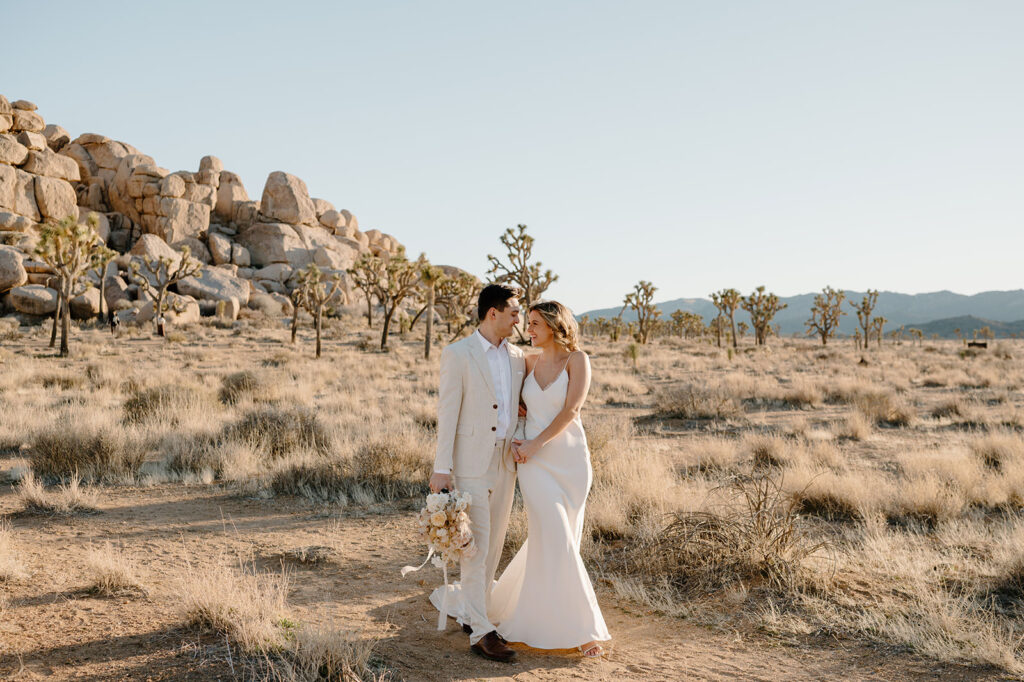 A bride and groom smile at one another while eloping in Joshua Tree National Park