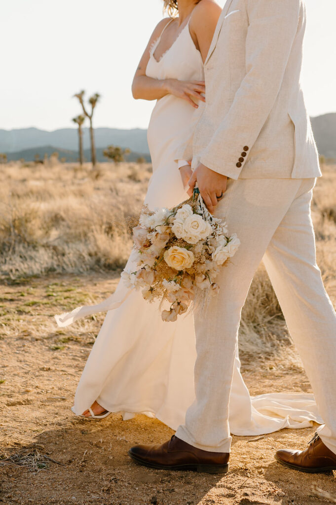 A bride's husband holds her wedding florals during their Joshua Tree wedding ceremony