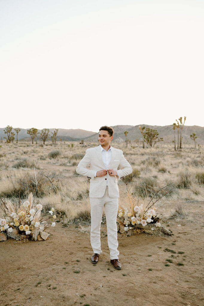 A man buttons his suit jacket before getting eloped in Joshua Tree