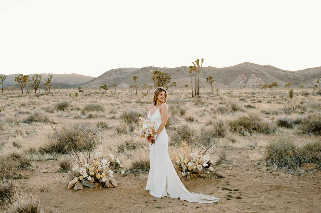 A bride poses with neutral wedding florals in Joshua Tree