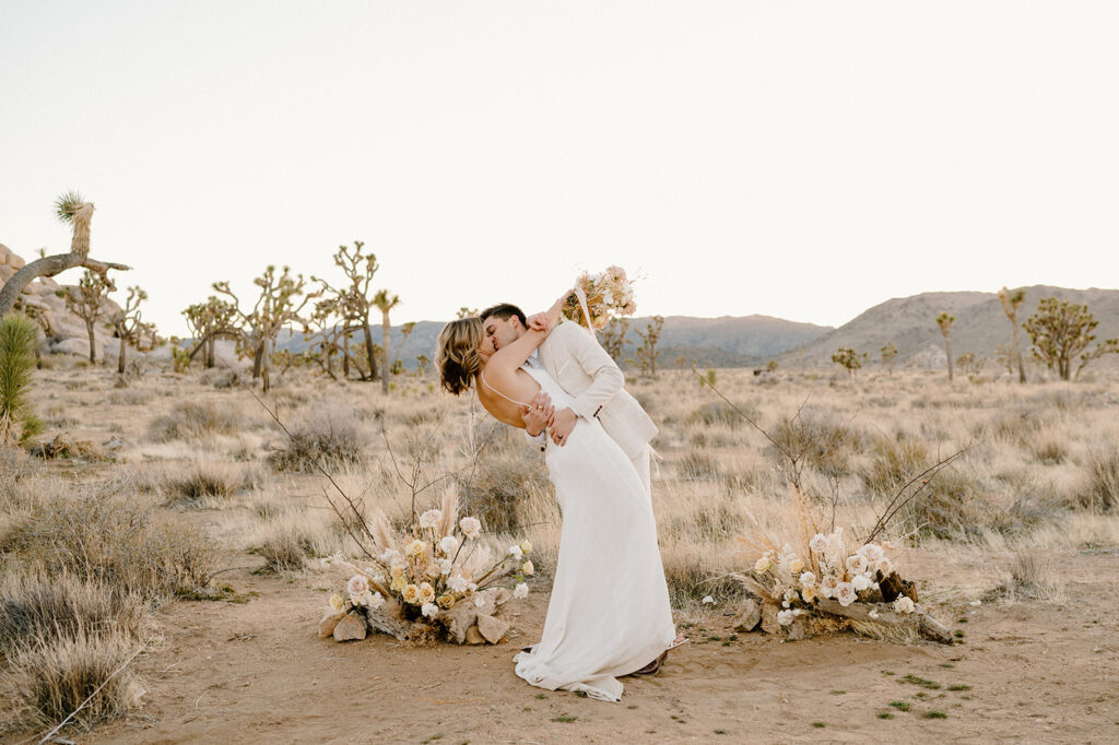 A husband kisses his wife during their intimate elopement ceremony in the desert