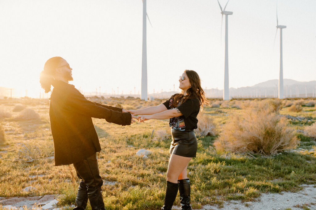 A couple twirls on a roadside near a windmill farm near Palm Springs, California