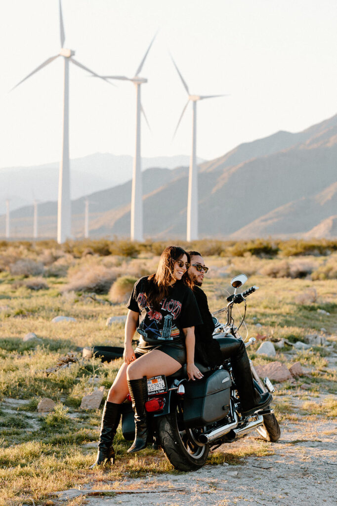 A couple poses on a motorcycle near a windmill field just outside of Palm Springs