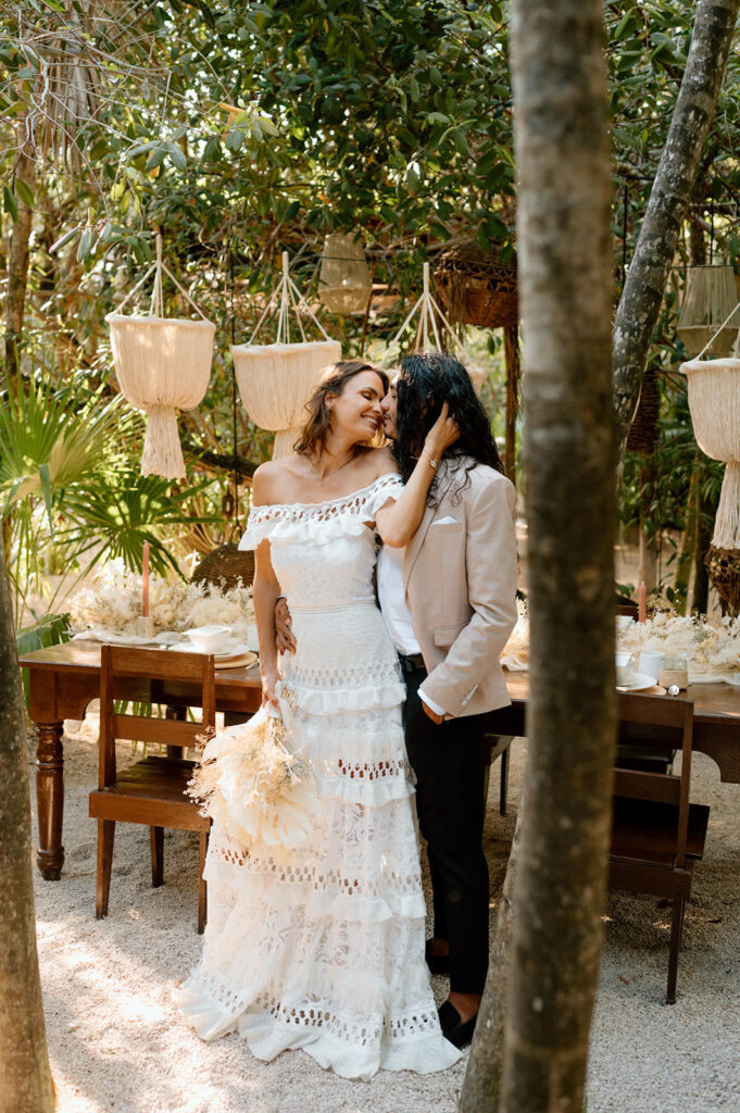 A couple embraces and kisses in the jungle of Tulum during their elopement reception