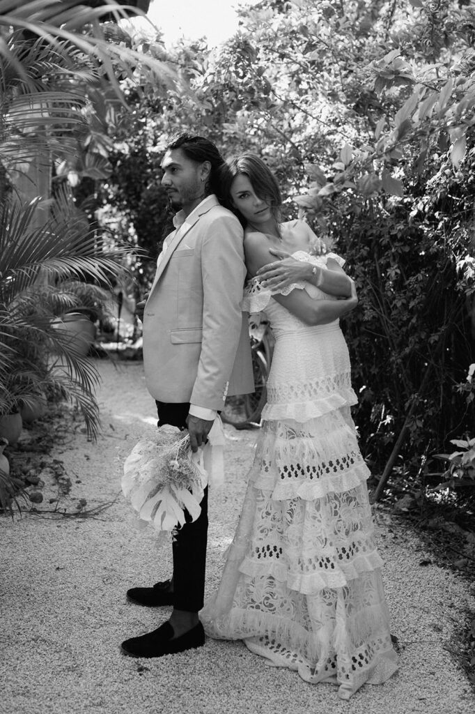 A couple leans on one another in a Mexico jungle reception space for their wedding