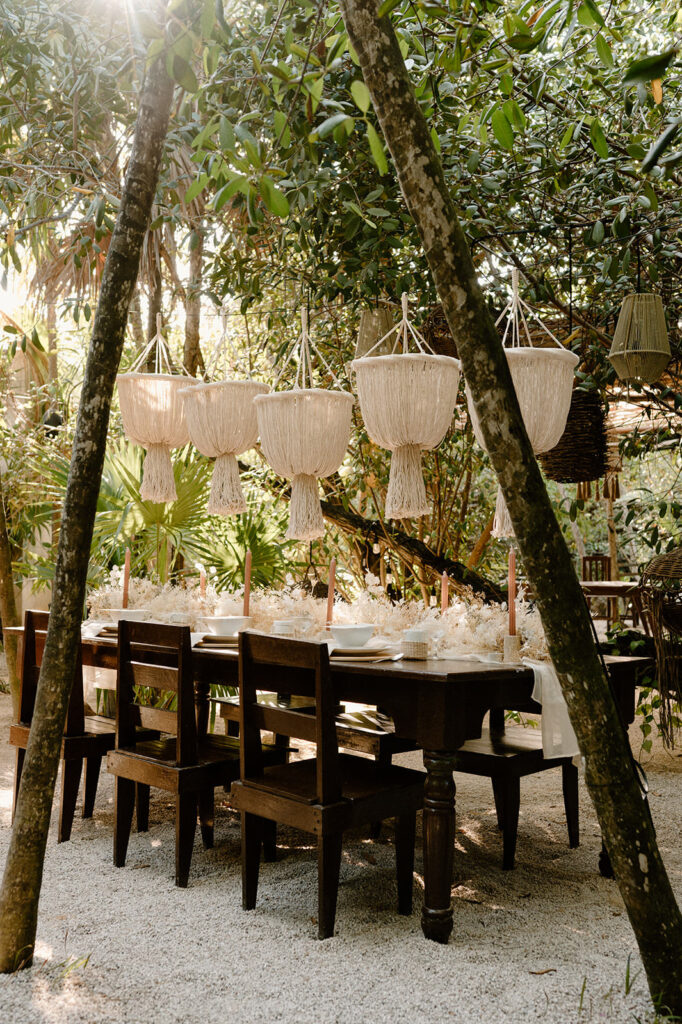 A tablescape is seen in a jungle in Tulum at a beach wedding venue on the sand