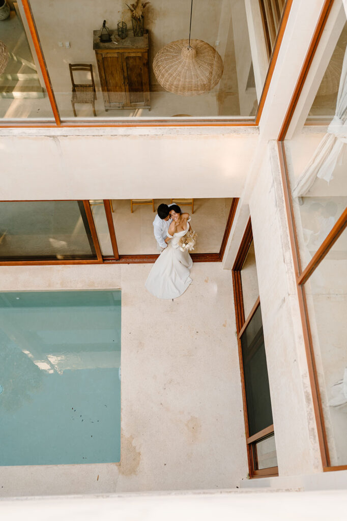 A couple poses by a pool at an Airbnb in Tulum in wedding attire