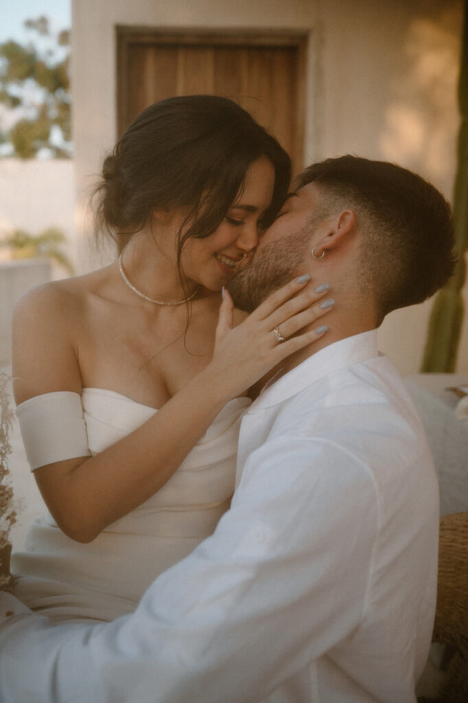 A couple kisses at an Airbnb in Tulum celebrating their destination tropical wedding