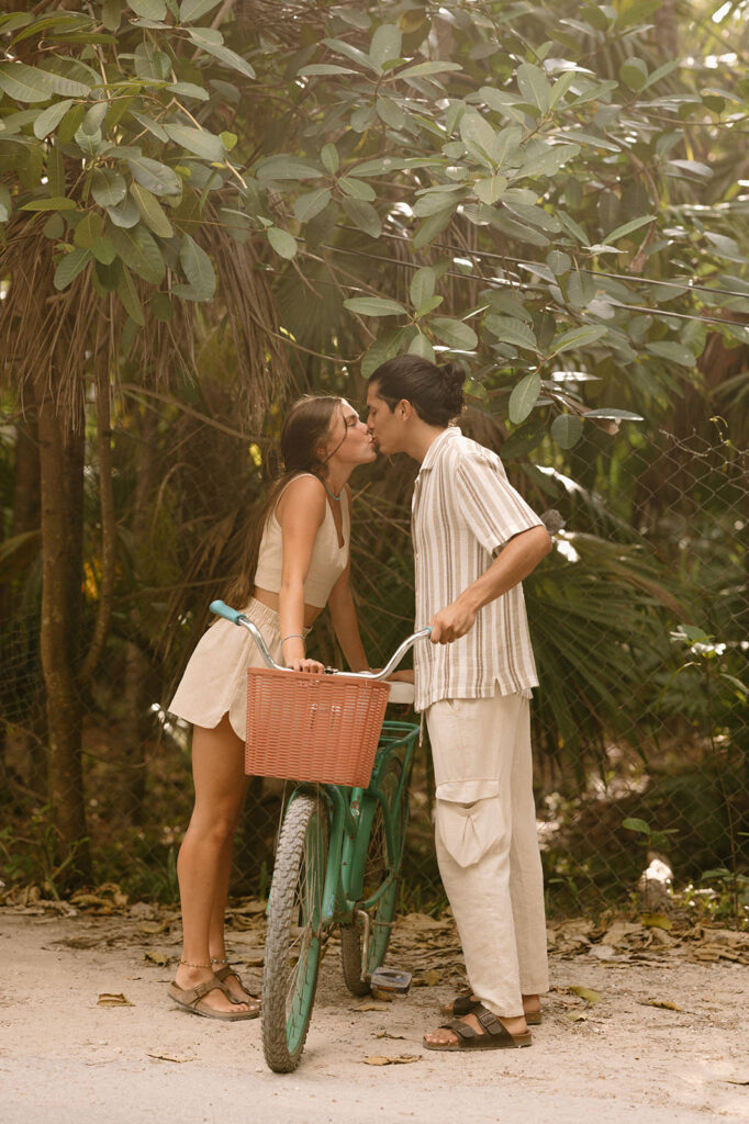 A couple kisses while leaning over a bike in Tulum during their elopement