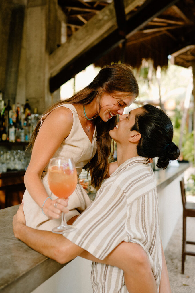 A couple kisses at a tropical bar during their Tulum engagement session