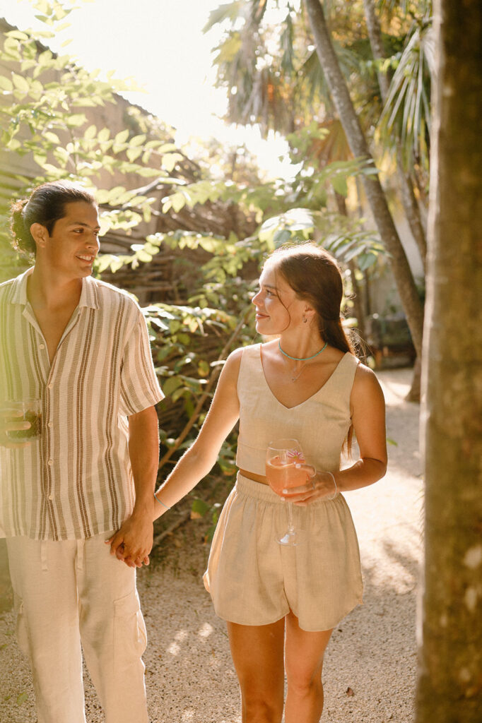 A couple walks hand in hand during their Tulum engagement in the jungle