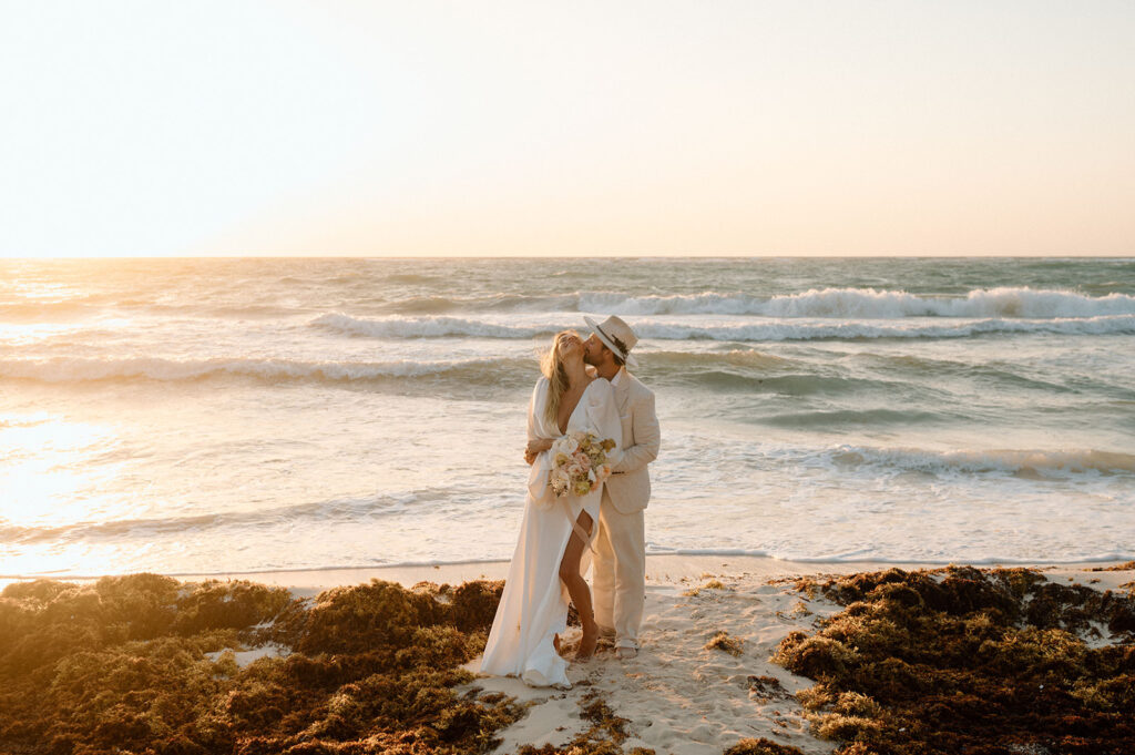 A couple embraces on a beach at Sunset in Mexico in beachy elopement attire. 