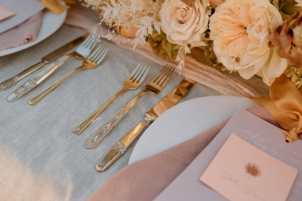 A tablescape is seen with neutral, dried wedding florals and pink accents.