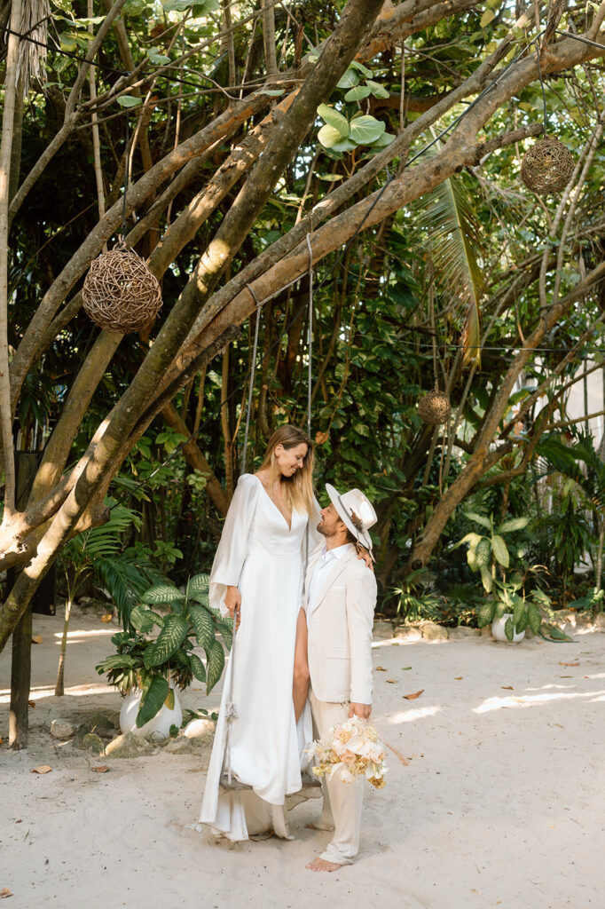 A couple stands in a sandy jungle in wedding attire during their tropical elopement