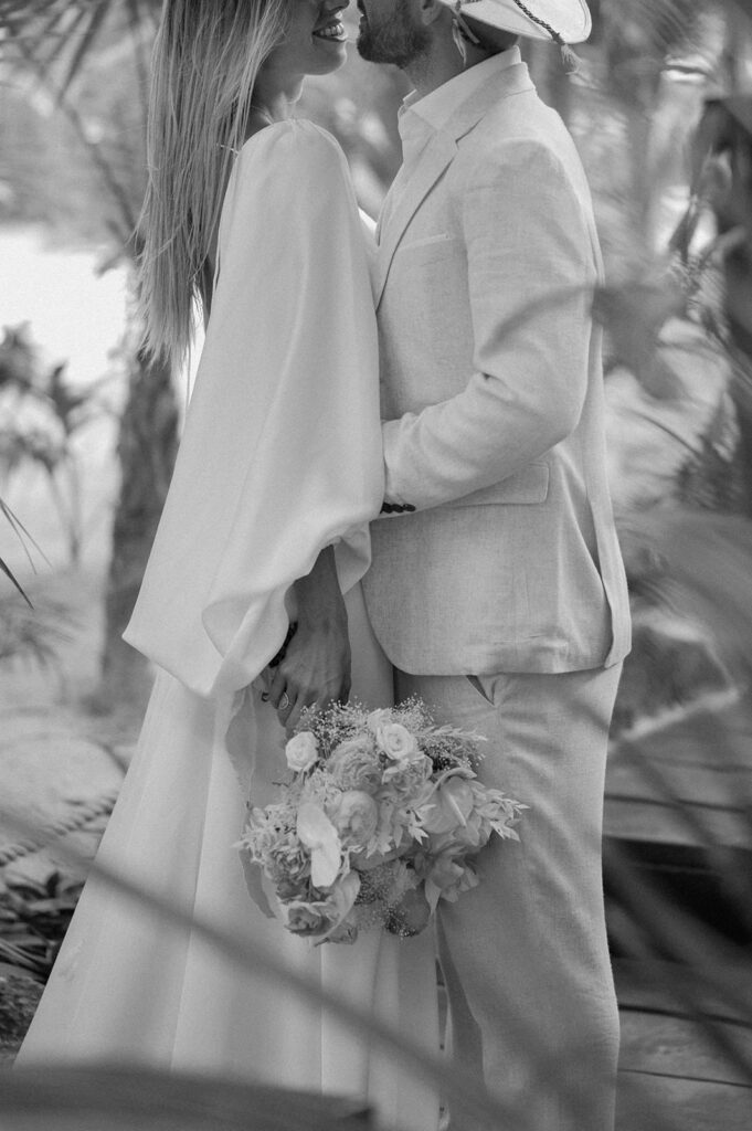 A couple embraces in a jungle in wedding attire just before their Tulum elopement