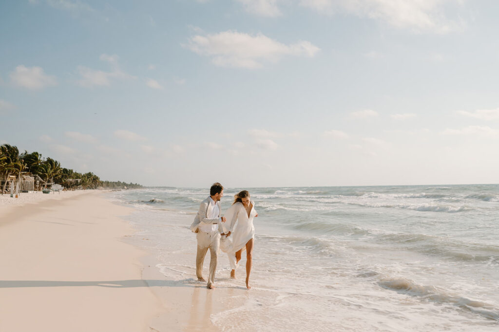 A couple runs along the beach after eloping in Tulum, Mexico