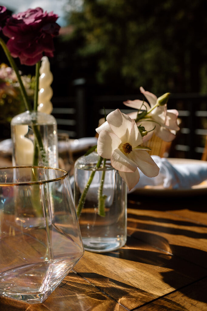 Delicate floral arrangements are in jars on a rustic wedding tablescape.