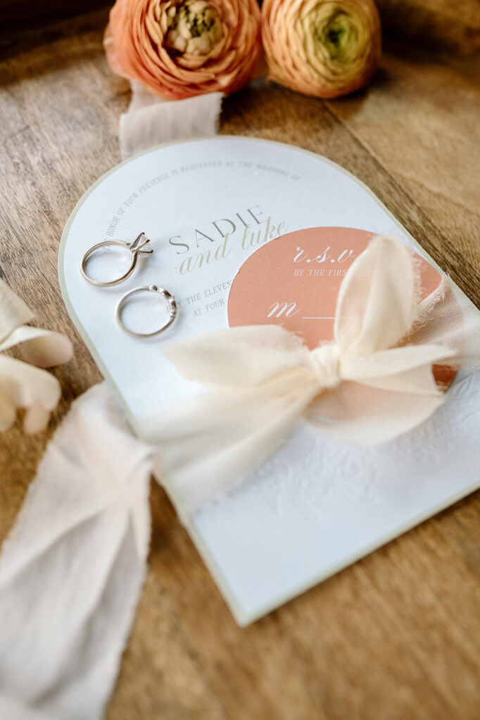 An invitation suite for an elopement at Harmels On The Taylor is seen on a wooden table.