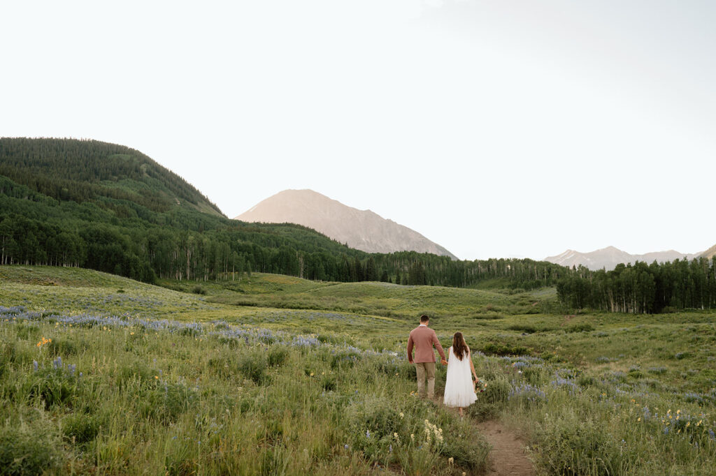 A couple walks towards a mountain peak in Crested Butte after their Rockies elopement.