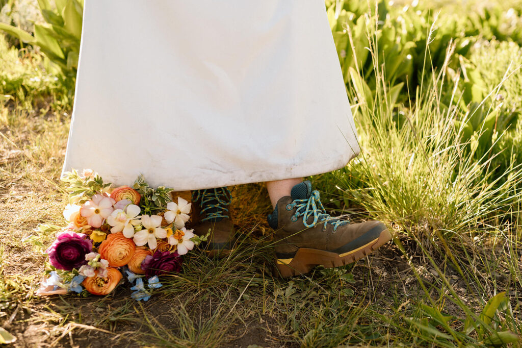 A bride shows off her hiking boots and wedding florals for her elopement at Harmels On The Taylor.