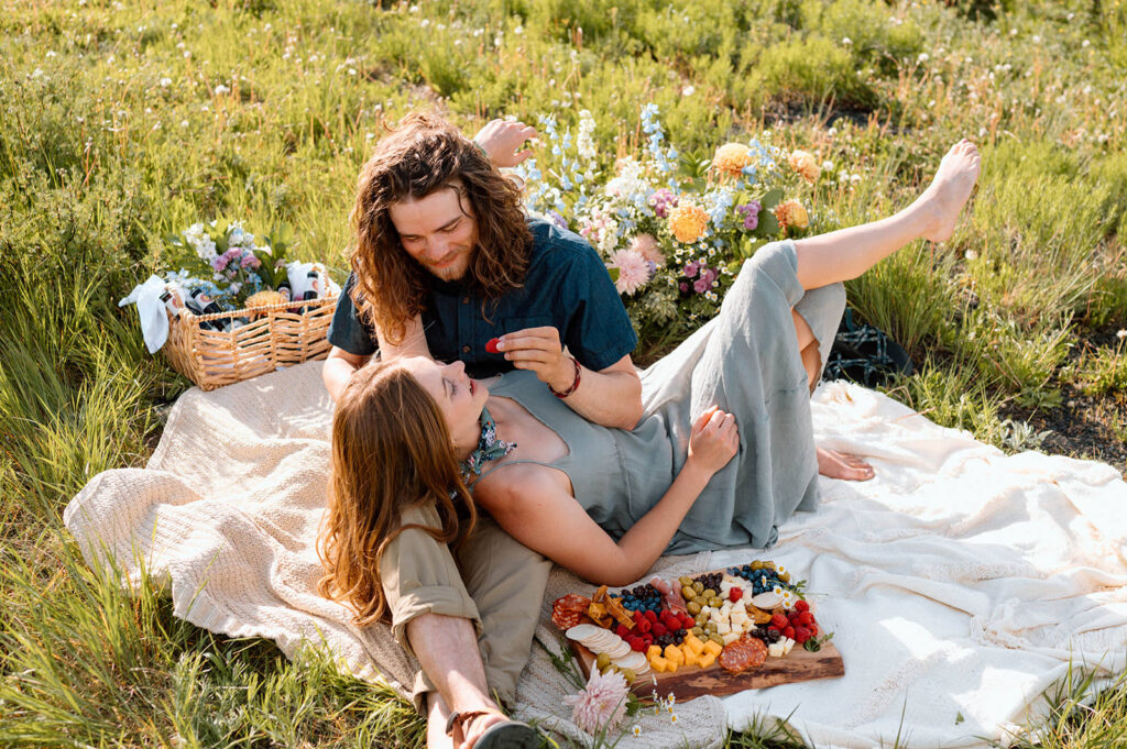 A couple shares a Summer picnic in a wildflower field in Colorado.