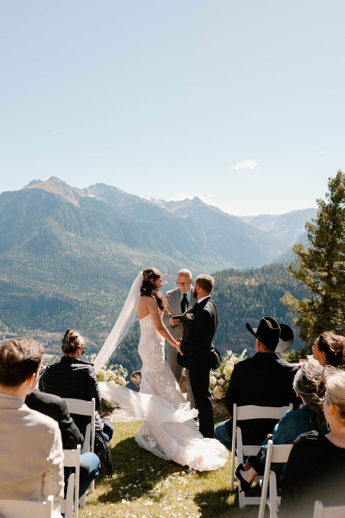 A couple holds hands while looking at their wedding officiant during their elopement in Ouray, Colorado. 