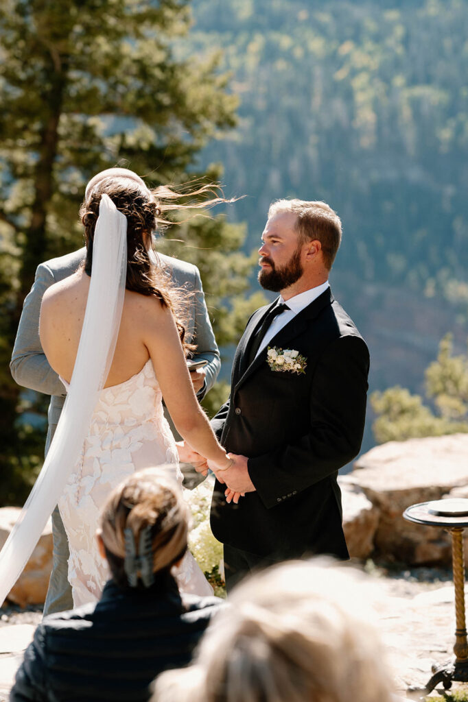 A groom admires his bride during a mountain top elopement.