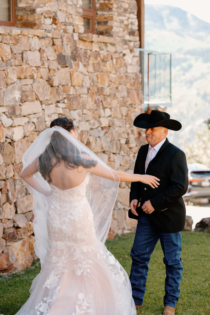 A woman in a wedding dress greets a man in a cowboy hat.