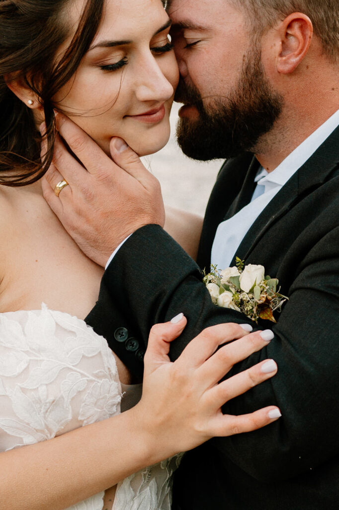 A couple embraces closely while wearing formal wedding attire. 