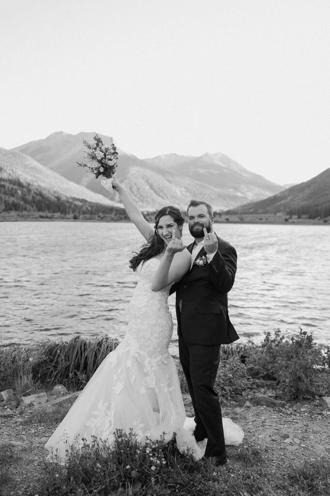 A couple shows off their wedding rings near an alpine lake in Ouray. 