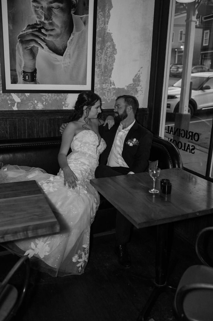 A couple shares a drink and sits in a booth celebrating their elopement at The Wester Hotel & Spa.