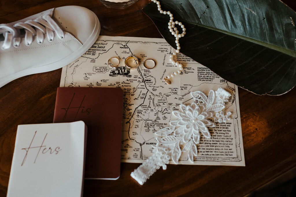 A rustic flat lay with vow books is on a wooden table. 