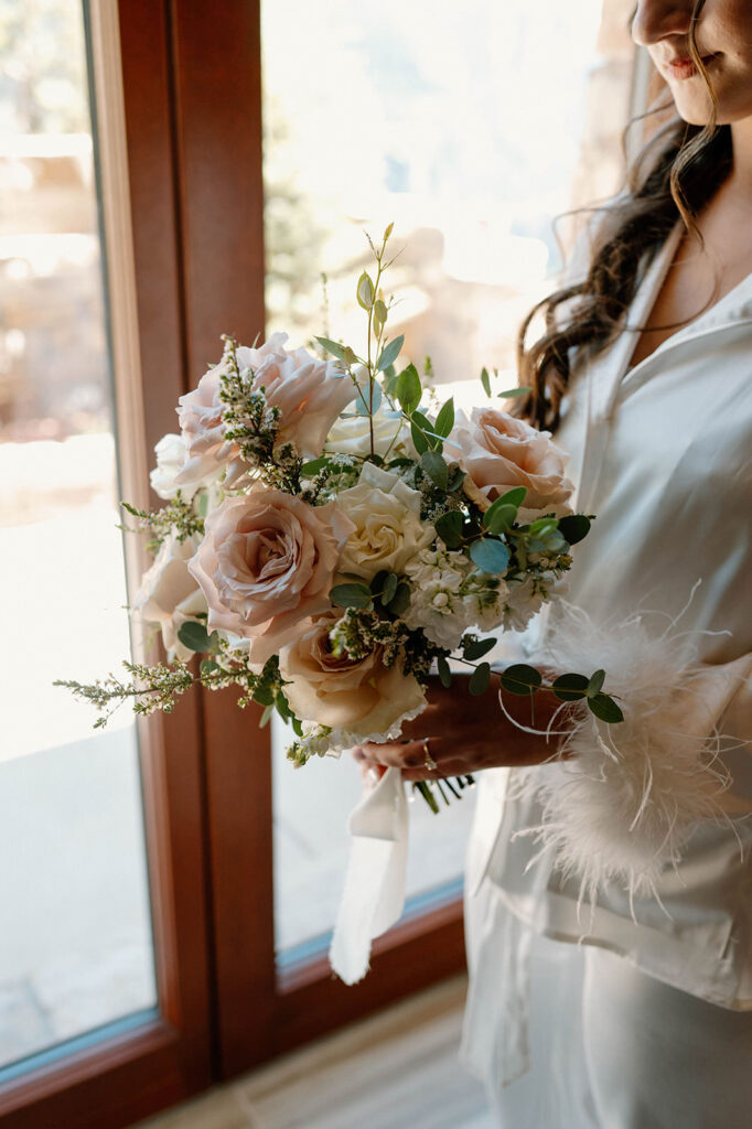 A neutral, pink bridal bouquet with roses and greenery.