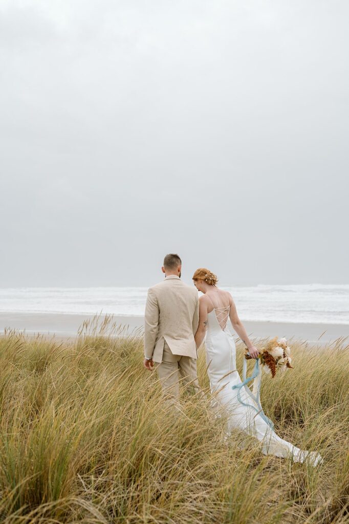 A couple walks along Cannon Beach to their wedding ceremony spot. 