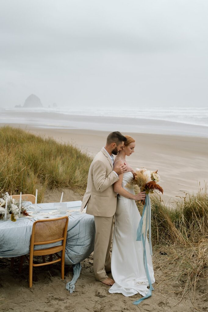 A couple poses next to a beach tablescape in Oregon. 