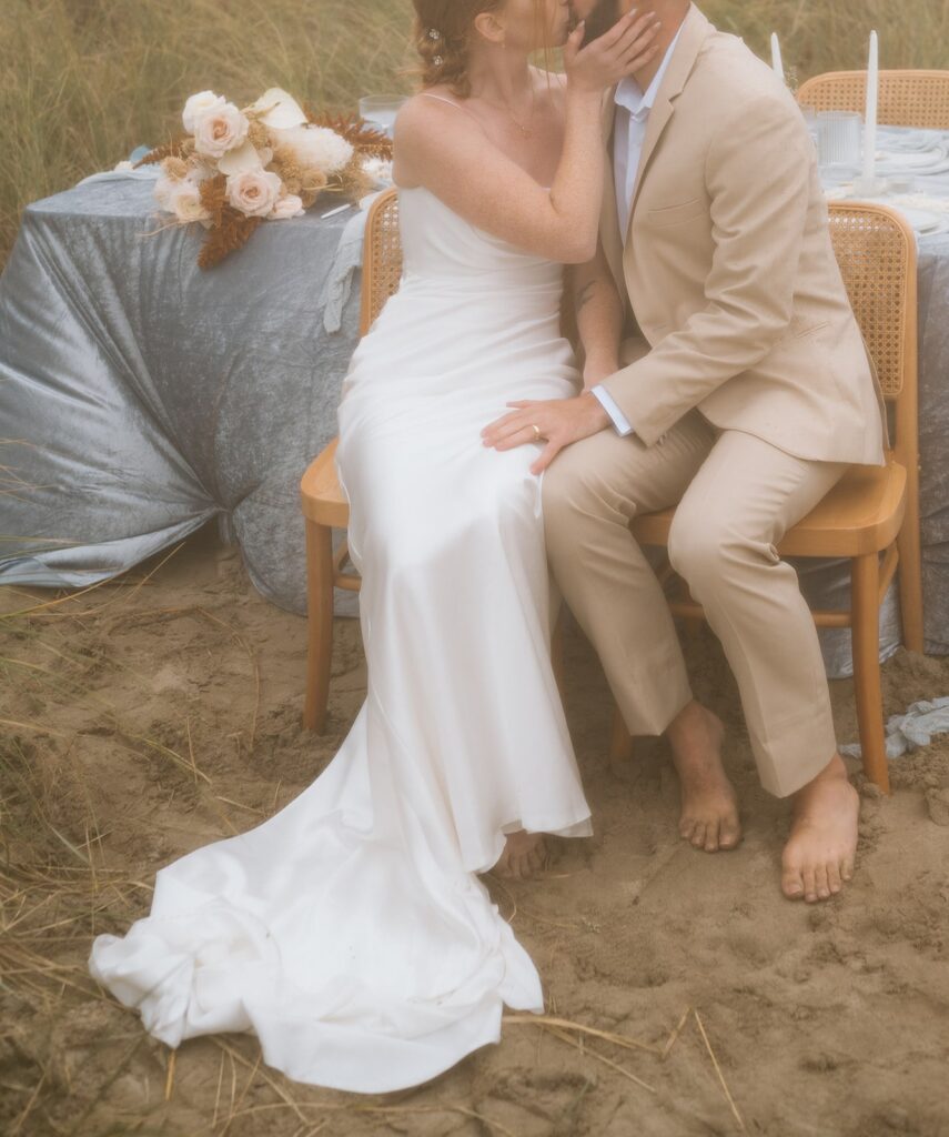 A couple wears neutral wedding attire during their beach elopement. 