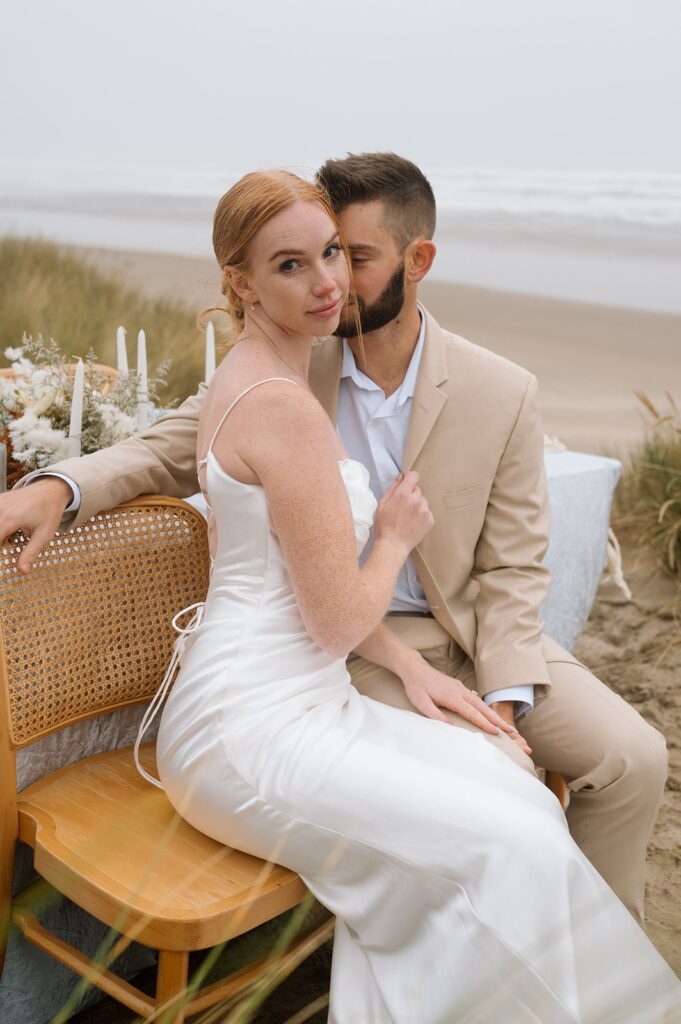 A couple sits in chairs on a beach in Oregon. 