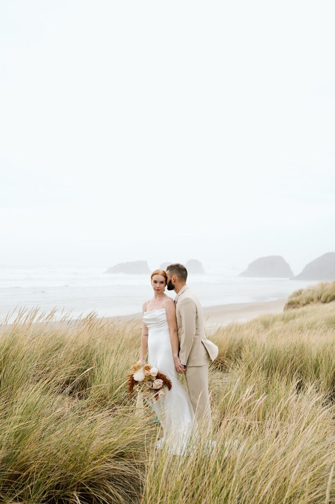 A groom kisses his bride on an Oregon beach. 