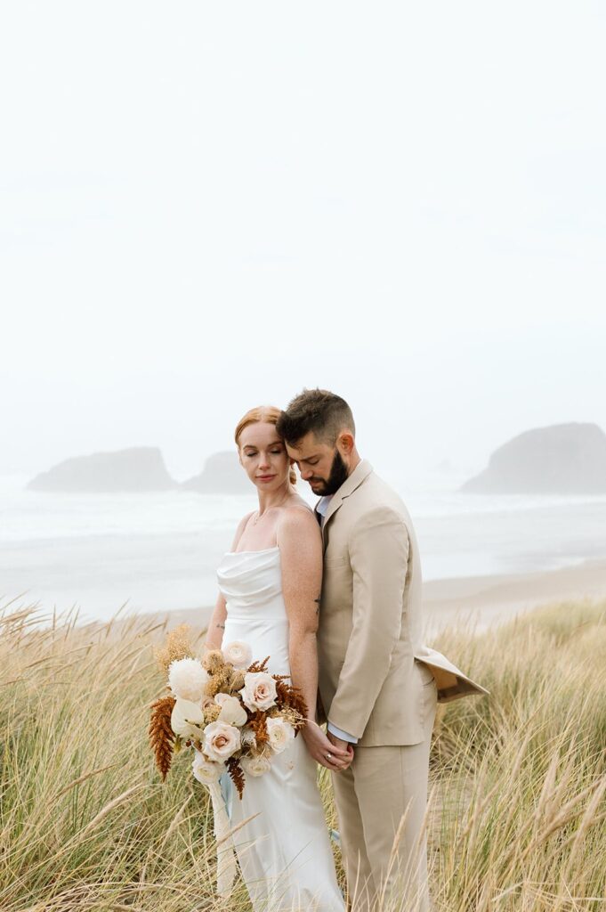 A couple elopes in tall sea grass in Oregon. 