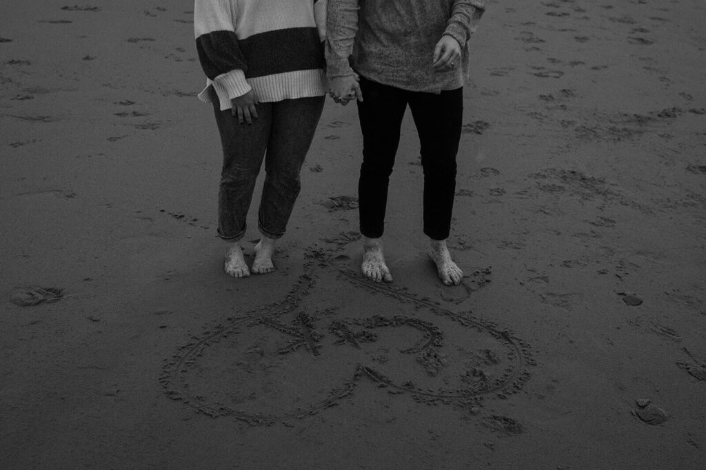 A couple admires their initials drawn in the sand on Cannon Beach. 