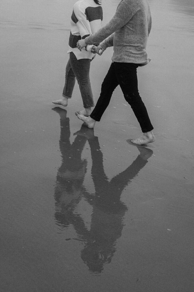 A couple walks along the sandy shores of an Oregon beach. 