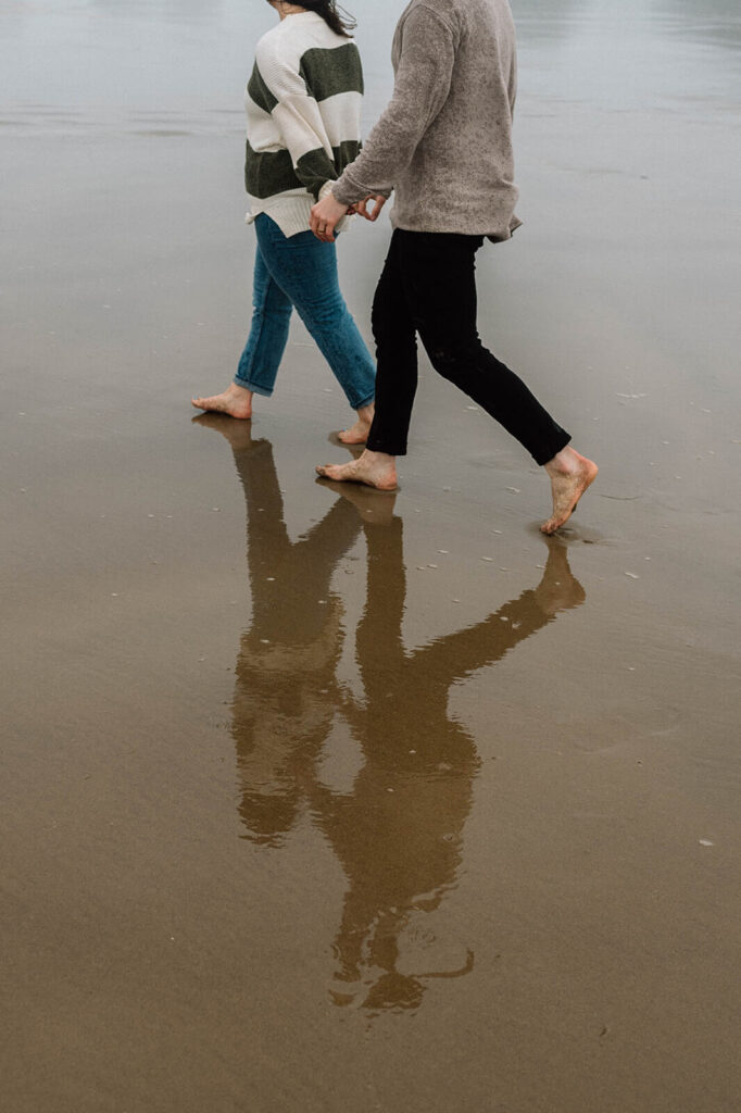 A couple walks hand in hand along Cannon Beach in Oregon. 