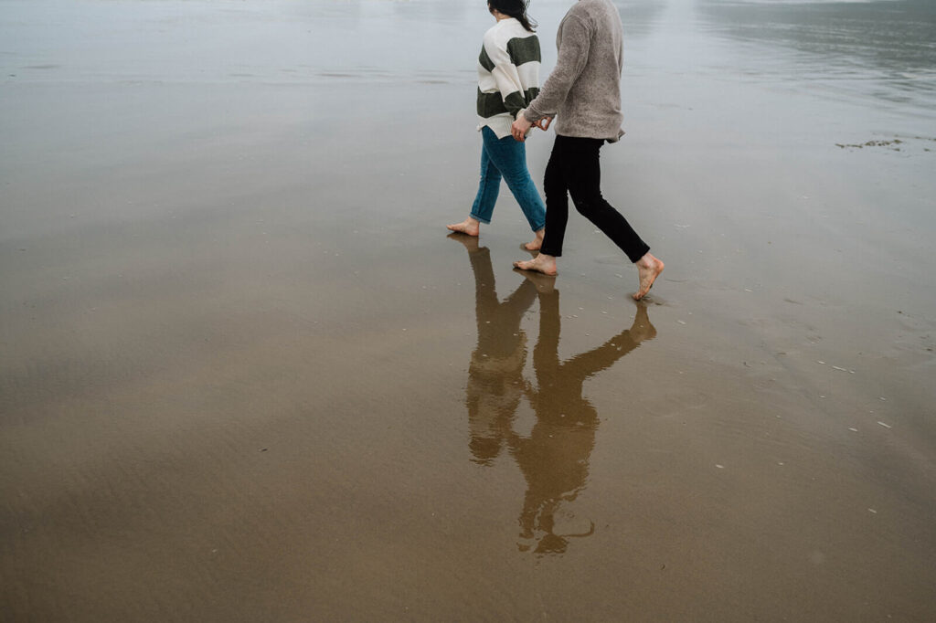 A couple wanders along a sandy beach in the Pacific Northwest. 
