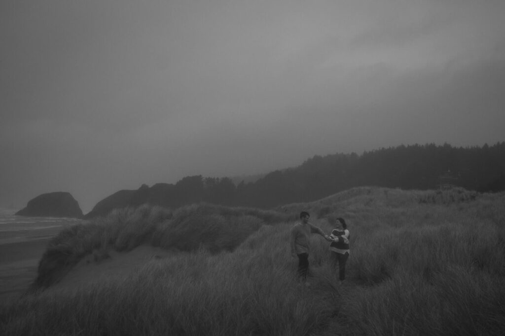A couple walks through seagrass along the Oregon coastline. 